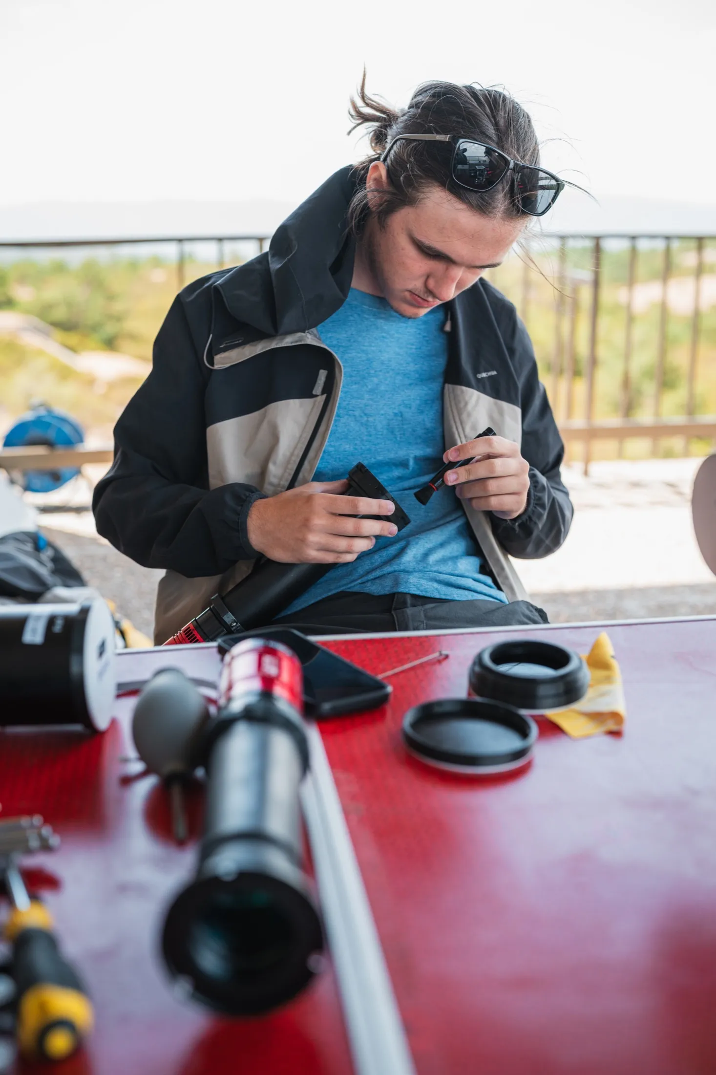 Hands assembling optical equipment on an outdoor table