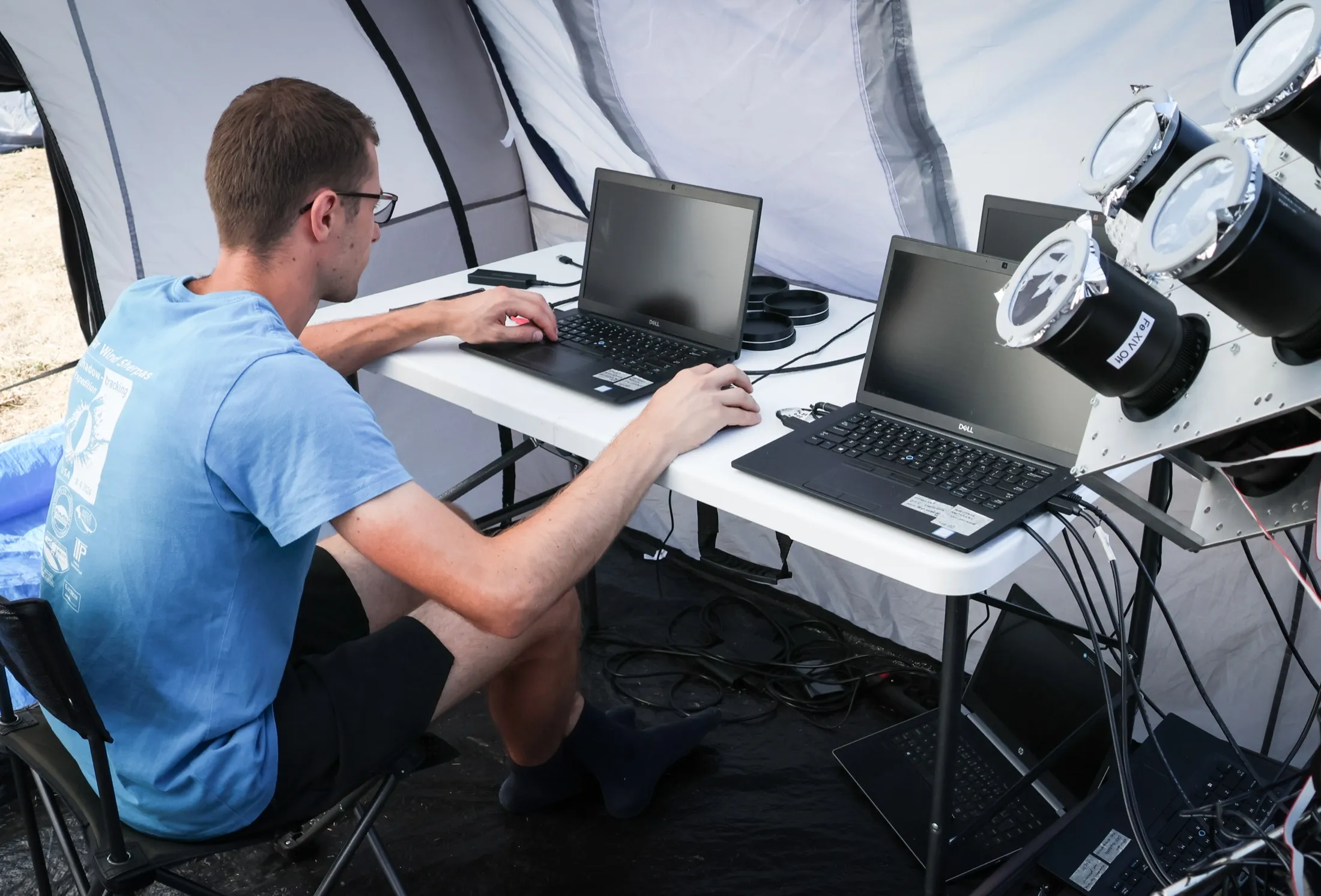 Researcher working at two laptops outdoors beside the instruments
