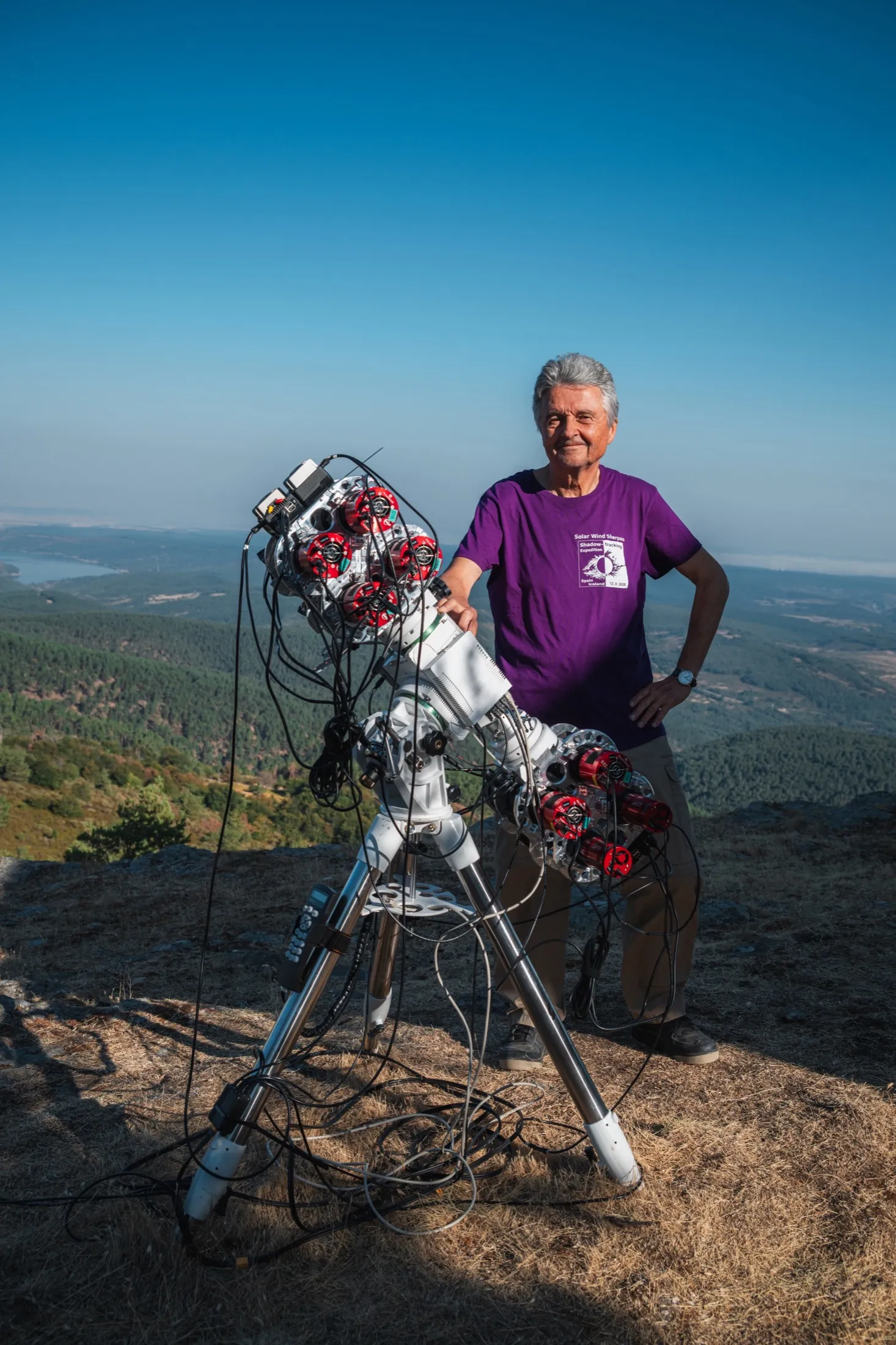 Researcher in a purple shirt beside the telescope array on the ridge