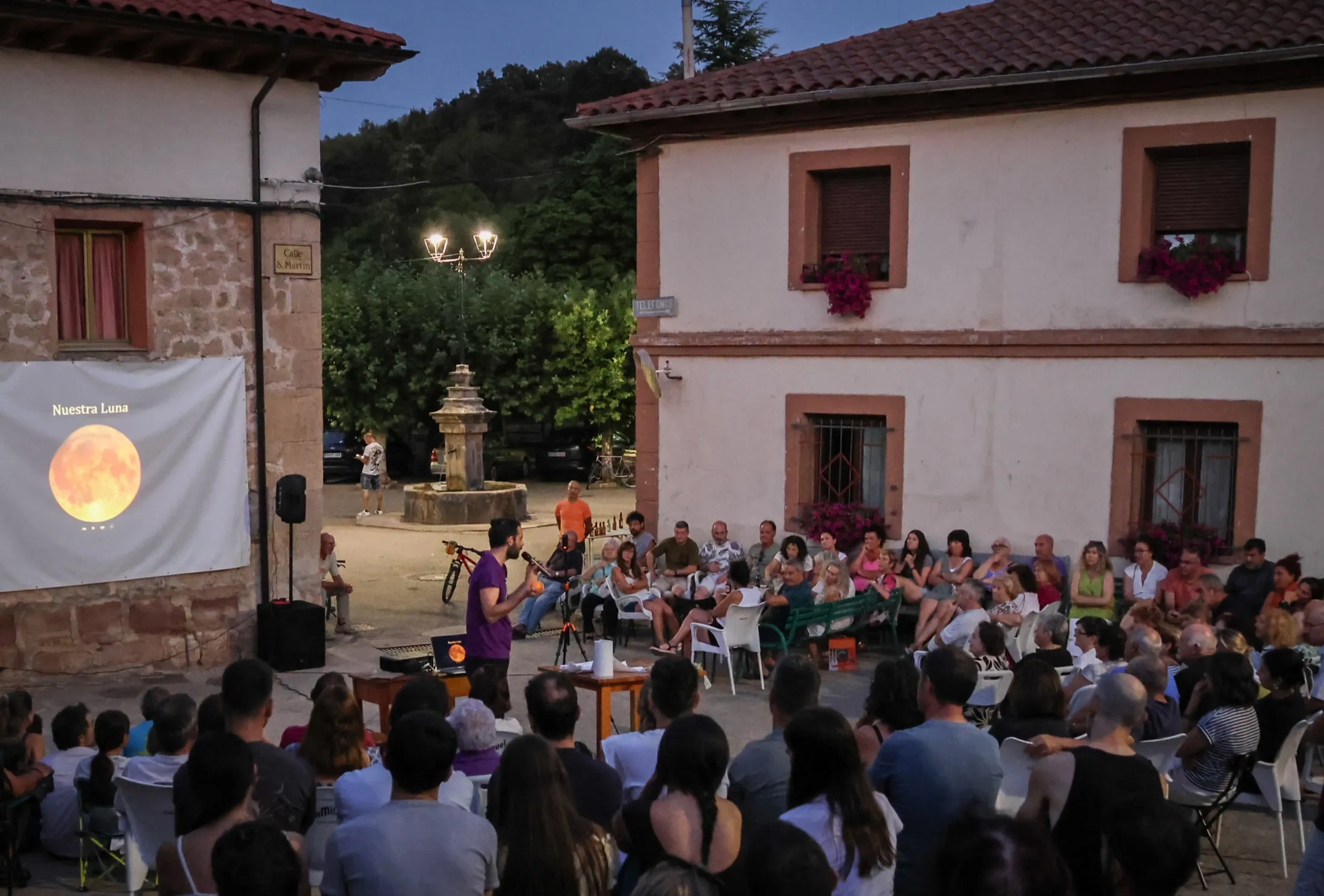 Outdoor public talk with a projection screen and local audience