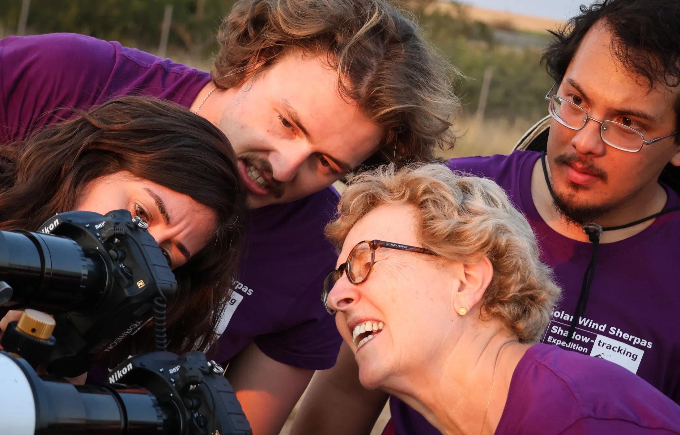 Four team members laughing together around a screen