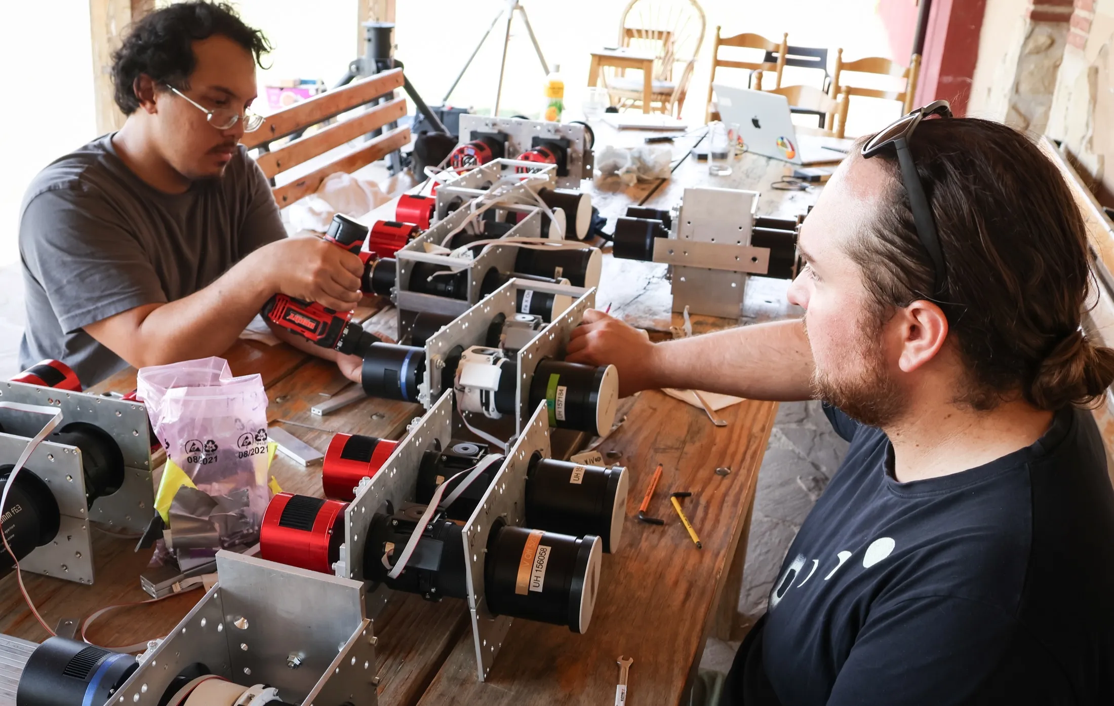 Two researchers assembling a multi-camera instrument array on a wooden table