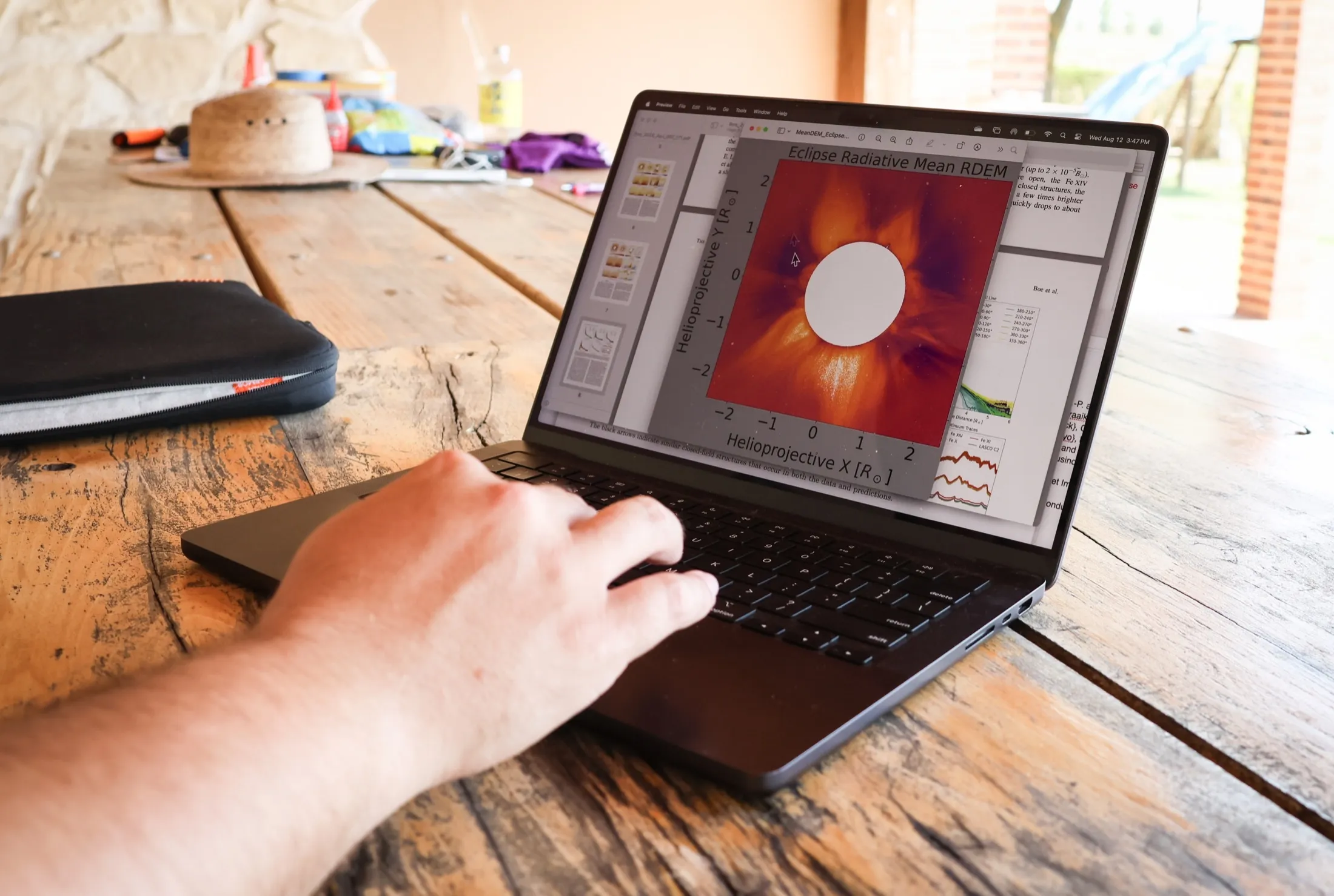 Laptop on a wooden table showing a processed image of the solar corona