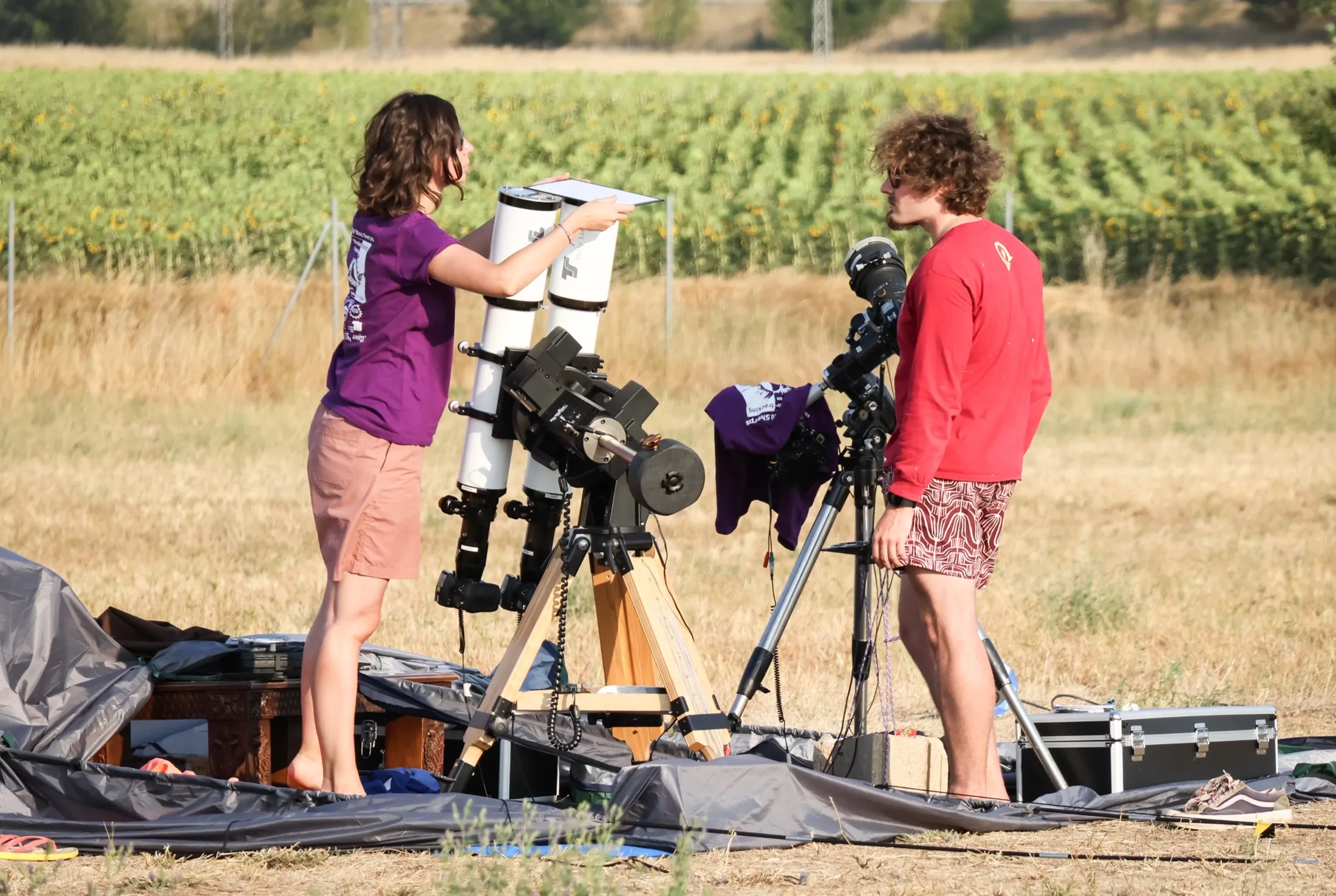 Team members setting up telescopes and camera rigs in open grassland