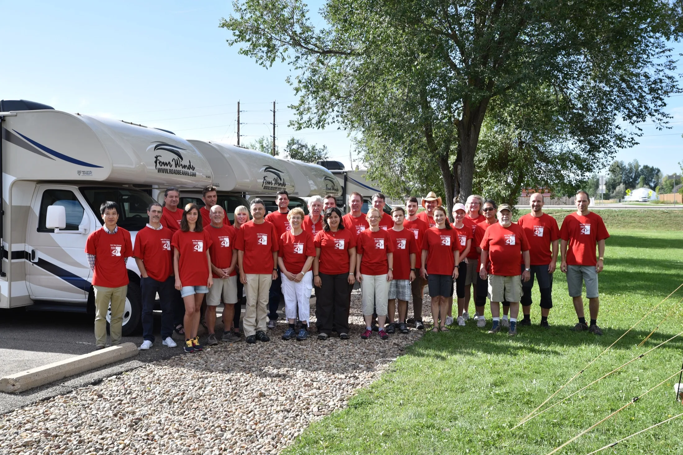 Large expedition group in red shirts in front of field vehicles