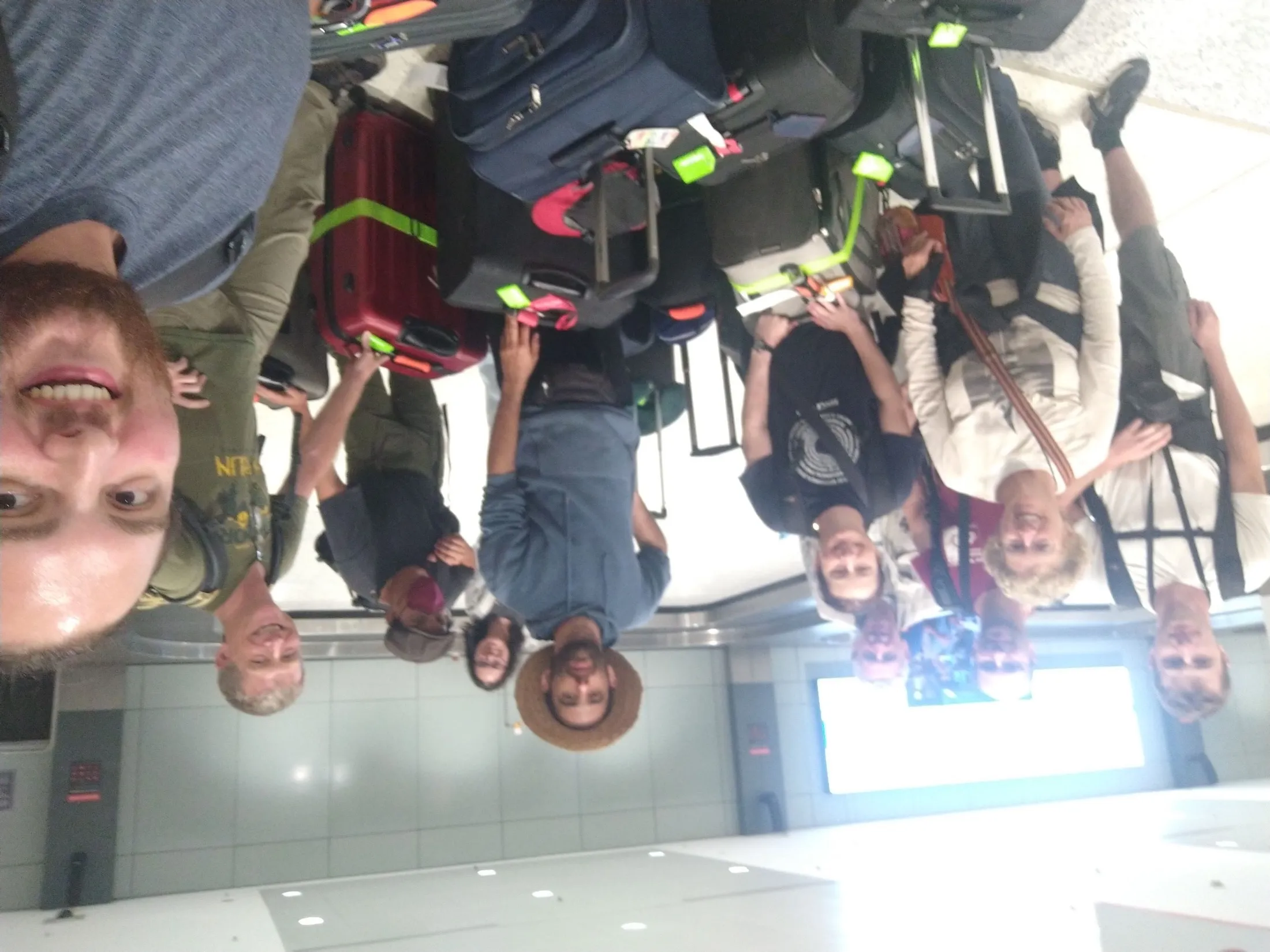 Team selfie with expedition luggage at an airport arrivals hall