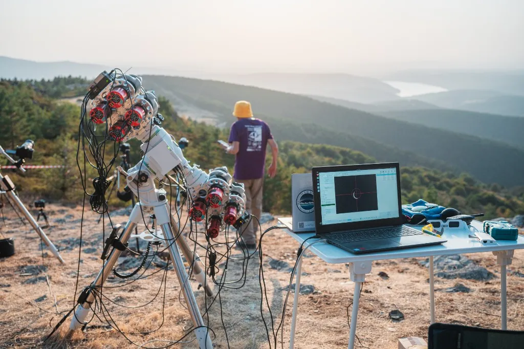 A multi-camera instrument rig and a field laptop on a ridge in Spain, with hills behind