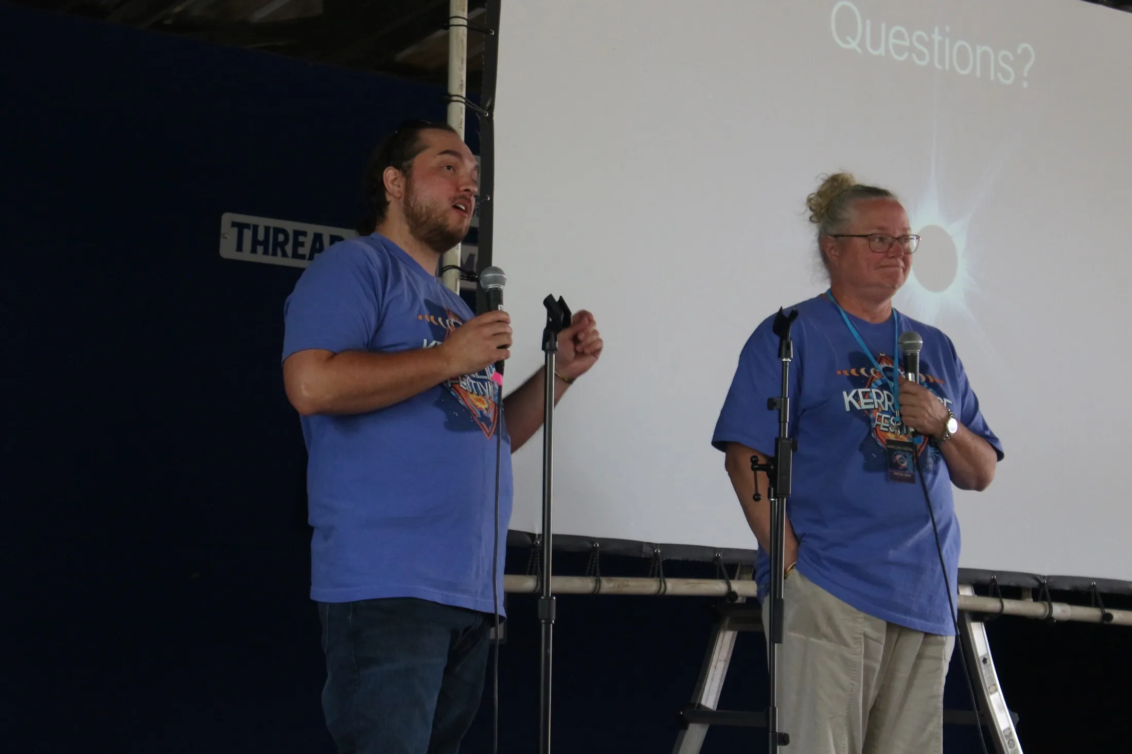 Ben and Martina speaking on stage with an eclipse slide behind them