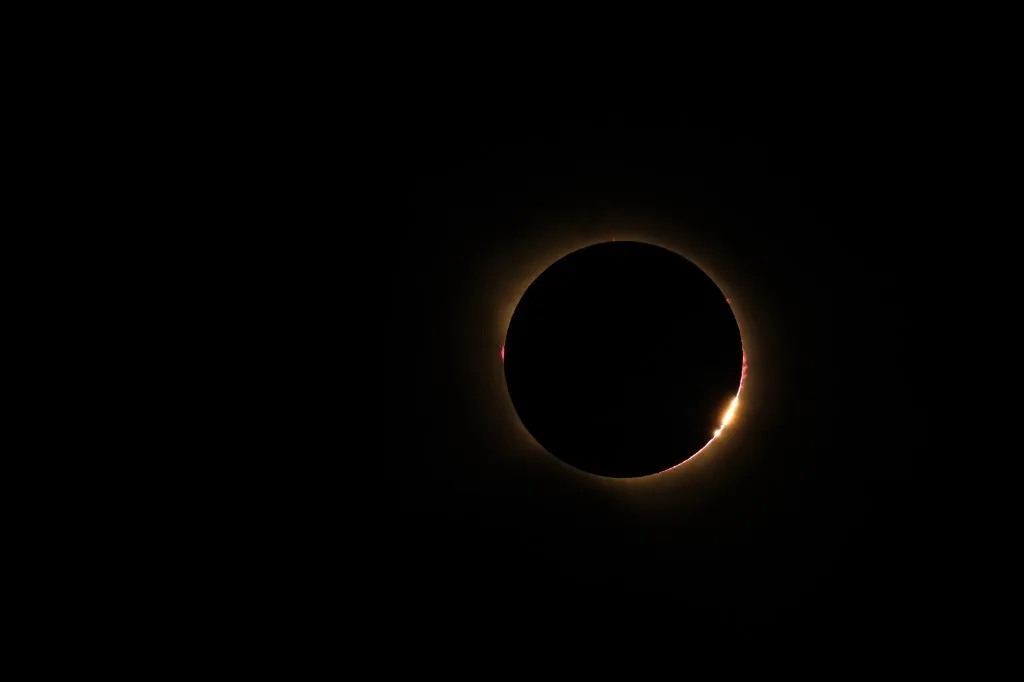 The Moon’s limb during totality, with pink prominences and a sliver of chromosphere