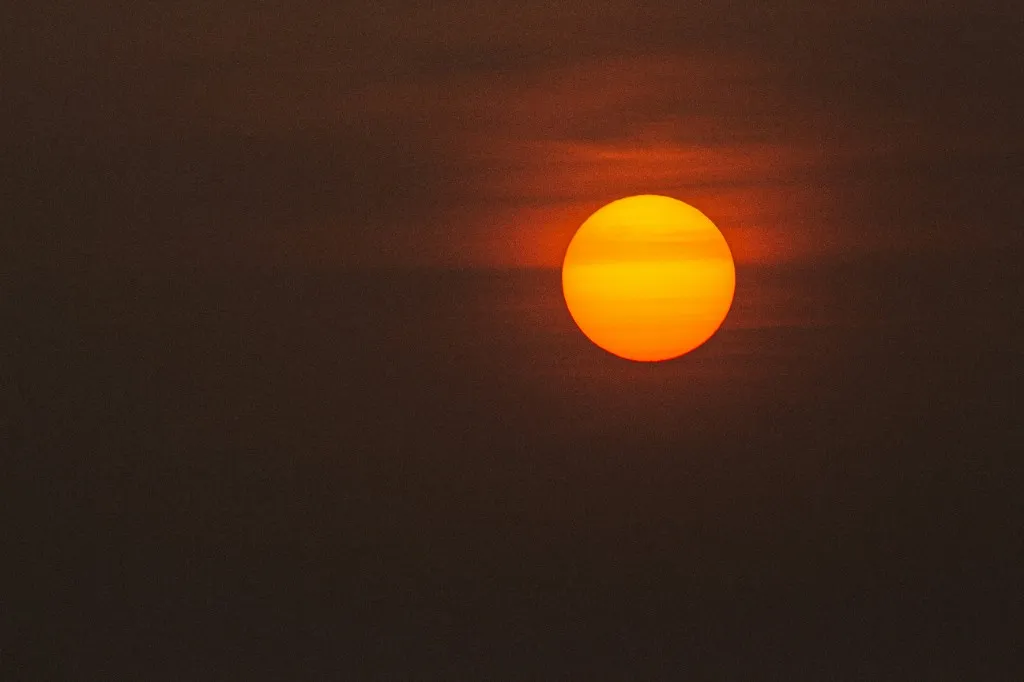 The uneclipsed Sun, a bright orange disk whose glare hides the corona