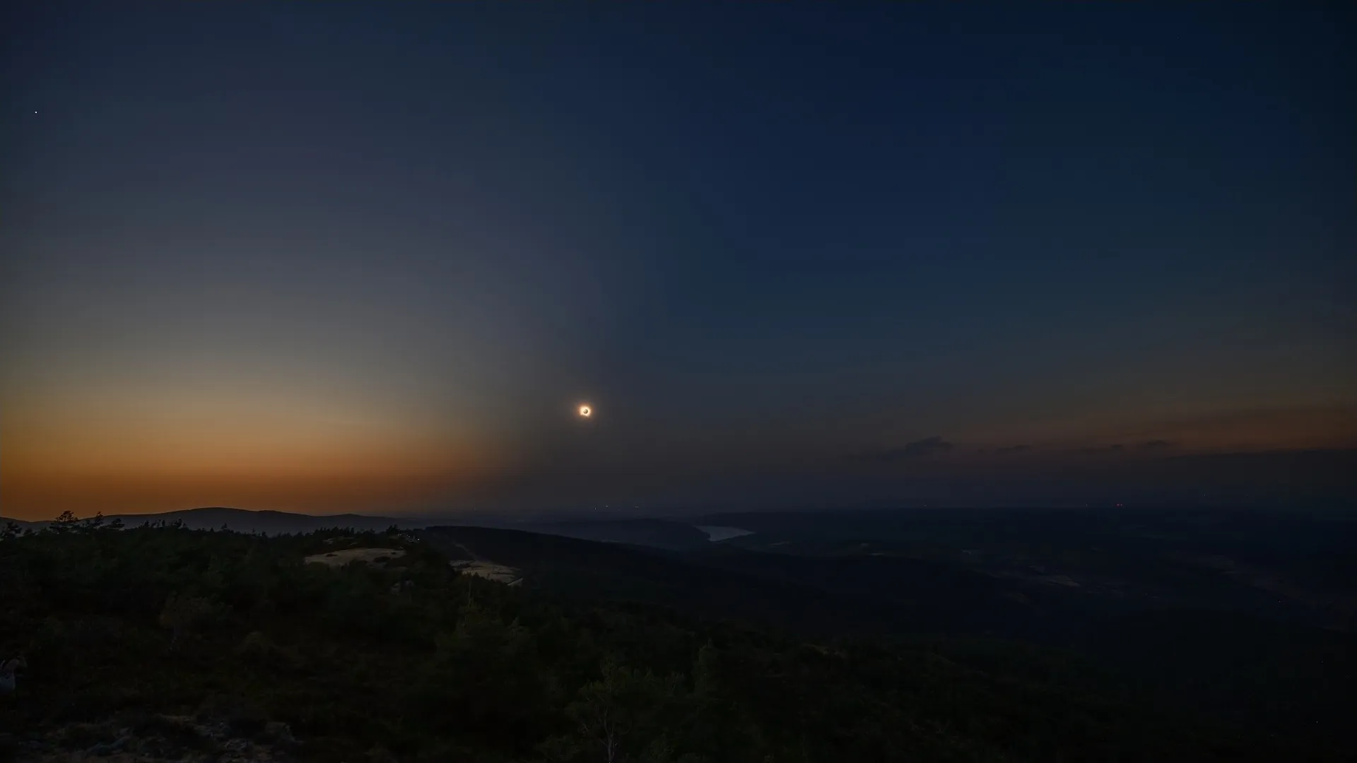Wide landscape view of second contact at Pico Trigaza with the eclipsed Sun low over the hills